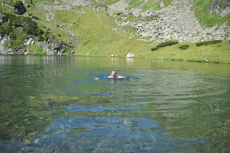 Hiker swimming in the ice-cold mountain lake Mittlerer Kaltenbachsee, Sölktäler Nature Park, Niedere Tauern, Styria, Austria, Europe