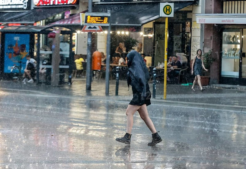 People run across Potsdamer Strasse in heavy rain. After weeks of heat, the first heavy rain brought cooling, Berlin, 15.08.2022