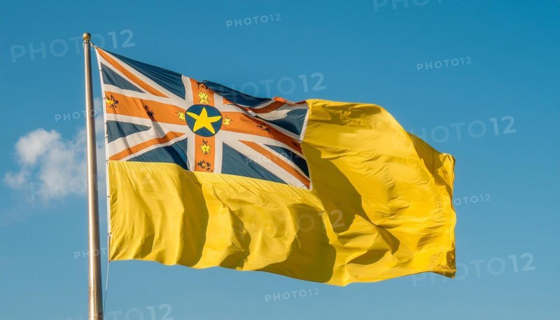 The flag of Niue, an island state in the Pacific Ocean, flutters in the wind, isolated against a blue sky