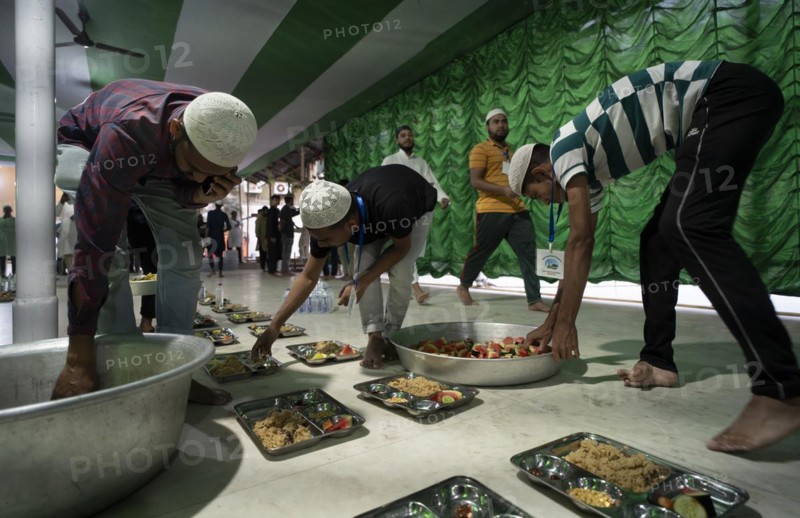 Volunteers distribute and arrange rows of 'iftar' meal for devotees to break their fast, during the holy month of Ramadan, at Burha Jame Masjid, on March 13, 2024 in Guwahati, Assam, India, Asia