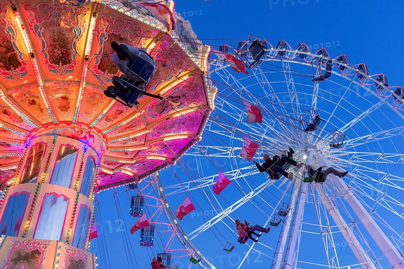 Illuminated chain carousel and Ferris wheel at night with cheerful people, funfair, wave flight, Cannstadter Volksfest, Stuttgart-Bad Cannstsdt, Baden-Württemberg