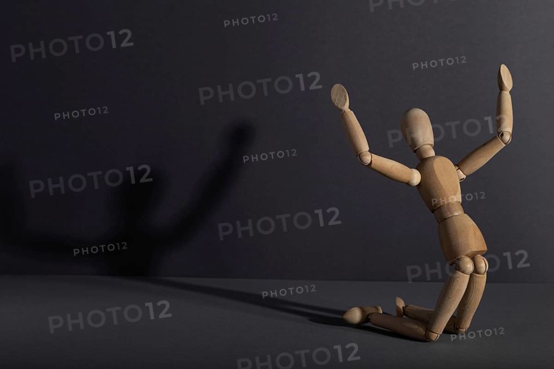 Wooden mannequin in imploration, praying position on gray background. religion, despair concept. copy space, hard light