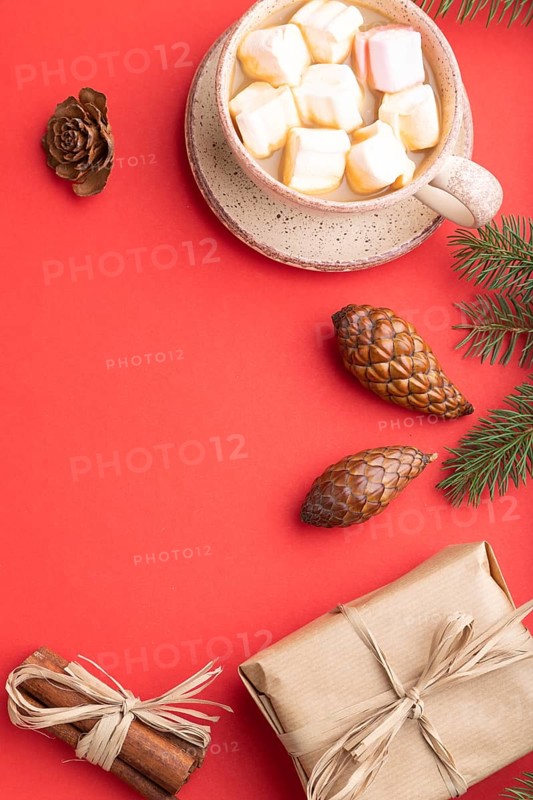 Christmas or New Year composition. Decorations, box, cinnamon, cones, fir and spruce branches, cup of coffee, on a red paper background. Top view, copy space, flat lay