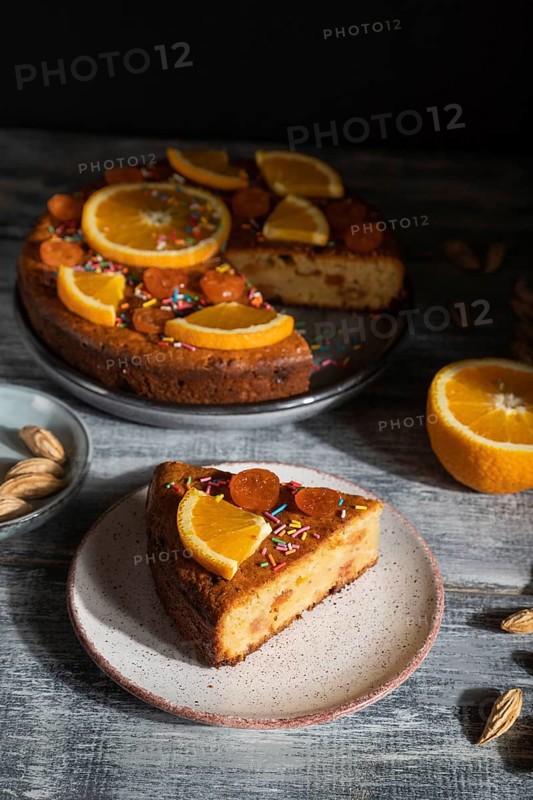 Orange cake on a gray wooden background. Hard light. contrast, low key. Side view, close up