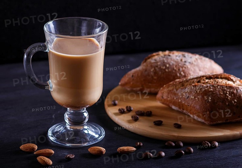 Glass cup of coffee with cream and buns on a black background. close up