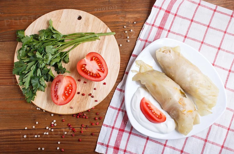 Cabbage rolls with beef, rice and vegetables on a linen tablecloth on a brown wooden background. top view, flat lay