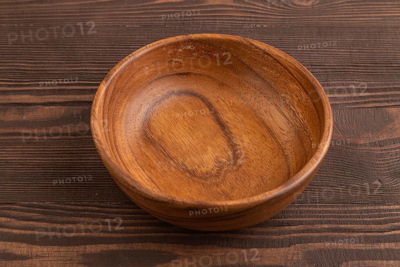 Empty brown wooden bowl on brown wooden background. Side view, copy space