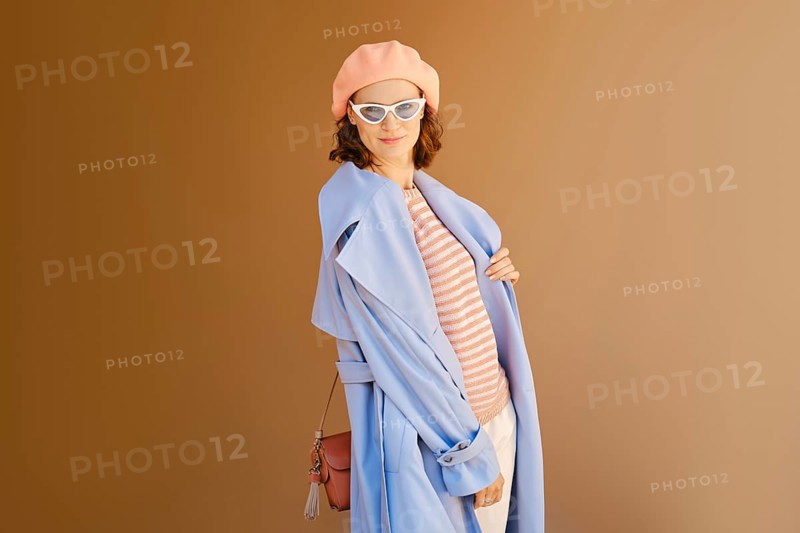 Lovely woman in coral beret and blouse, blue raincoat and sunglasses posing outdoor
