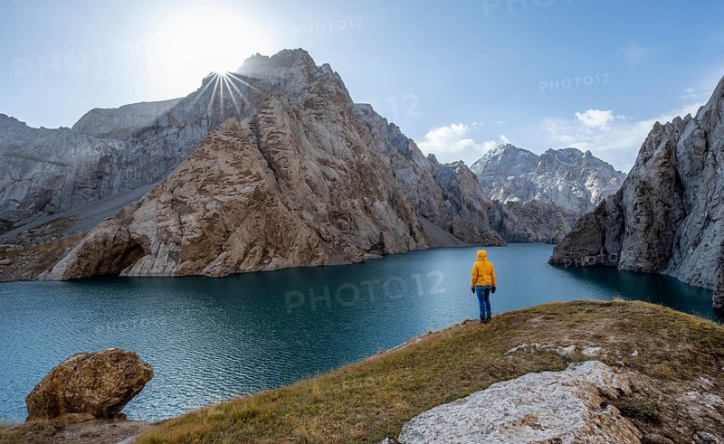 Tourist at the blue mountain lake between rocky steep mountain peaks, Sun Star, Kol Suu Lake, Sary Beles Mountains, Naryn Province, Kyrgyzstan, Asia