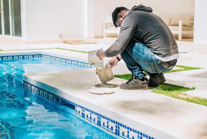 Man cleaning swimming pool garbage filter. Worker removing trash from swimming pool filter basket