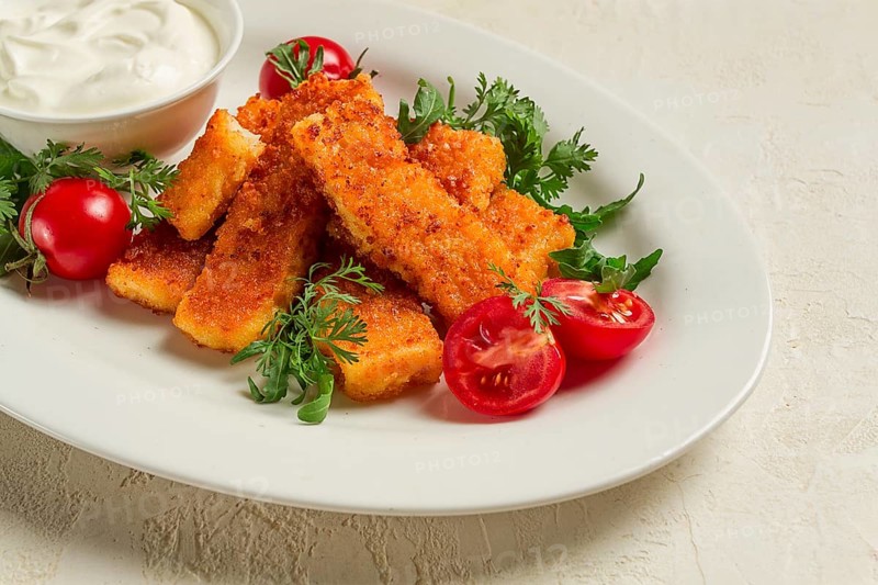 Fried fish nuggets, with white sauce, arugula and cherry, no people