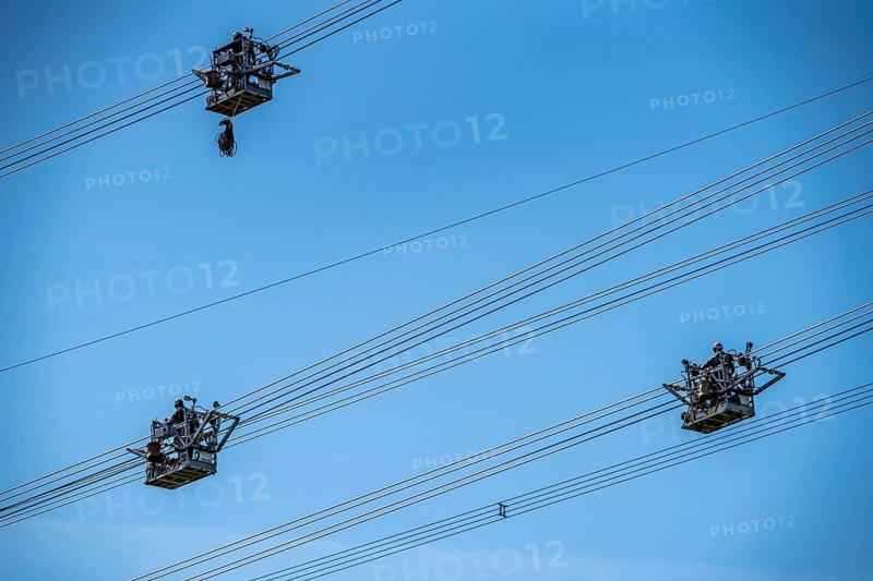 Construction of a new line route, 380 KV extra-high-voltage line between Osterath and Gohr, near Neuss, fitters in line trolleys, on the conductor cables, installing field spacers at great heights, North Rhine-Westphalia, Germany, Europe