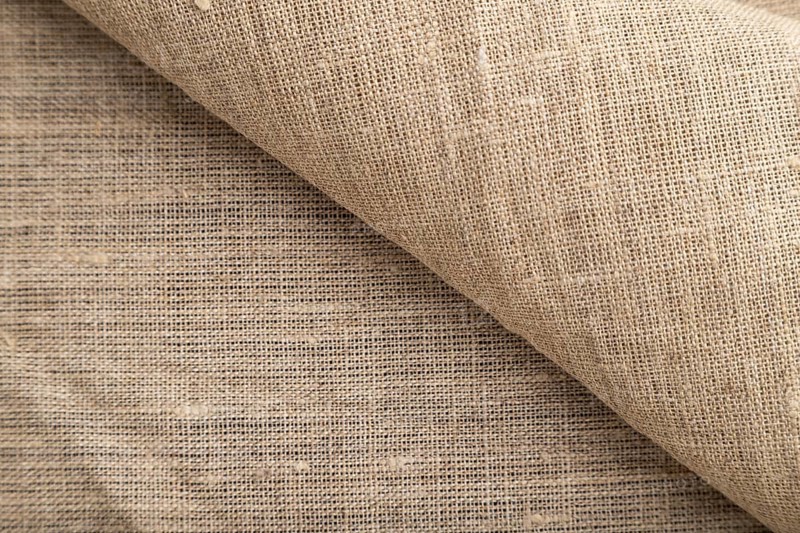 Fragment of rough linen tissue. Side view, natural textile background and texture
