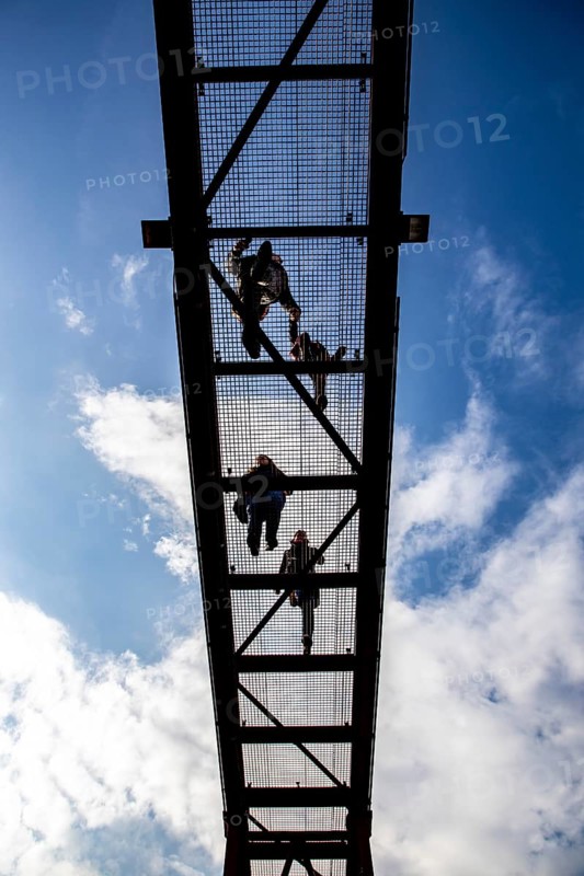 Lattice walkway, people walk over a walkway at a height of a good 15 metres, made of steel lattice, seen from below, viewing platform