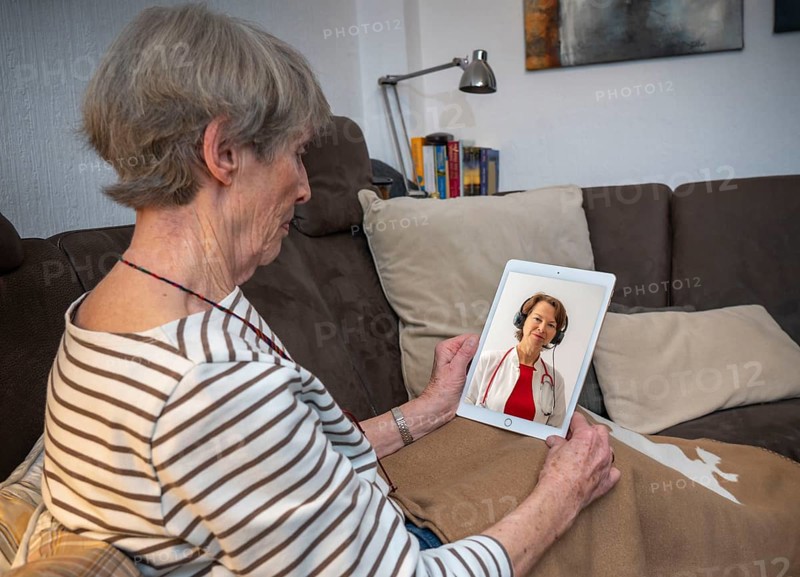 Symbolic image of telemedicine, patient speaking to a doctor in a video conference from home