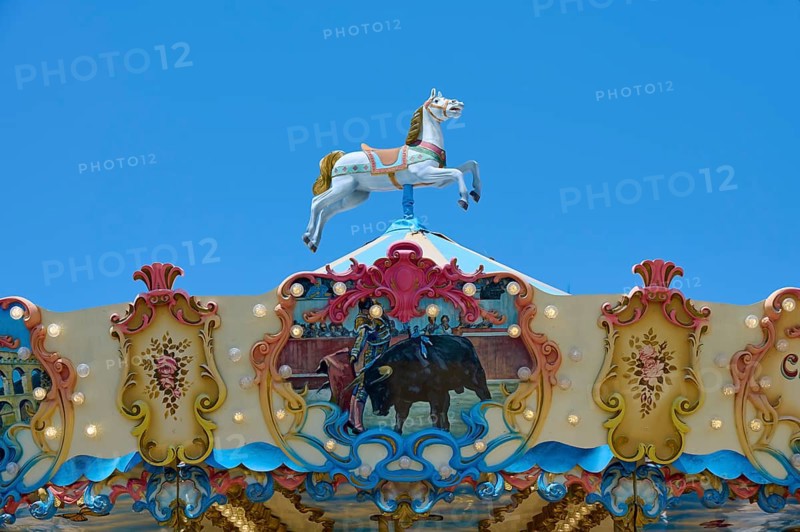 Colourfully decorated carousel with horse decoration under a clear blue sky, summer, Saintes-Maries-de-la-Mer, Camargue, France, Europe