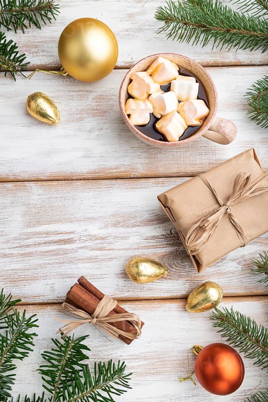 Christmas or New Year composition. Decorations, box, golden balls, cinnamon, fir and spruce branches, cup of coffee, on a white wooden background. Top view, copy space, flat lay