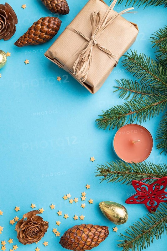Christmas or New Year composition. Decorations, box, cinnamon, cones, fir and spruce branches, cup of coffee, on a blue paper background. Top view, copy space, flat lay