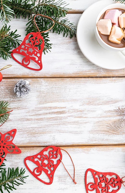 Christmas or New Year frame composition. Decorations, red stars, bells, cones, fir and spruce branches, cup of coffee, on a white wooden background. Top view, copy space, flat lay