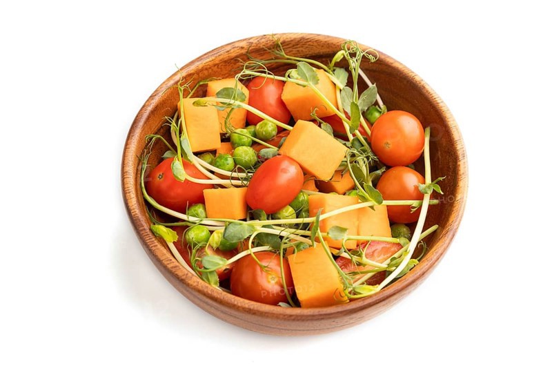 Vegetarian vegetable salad of tomatoes, pumpkin, microgreen pea sprouts isolated on white background. Side view, close up