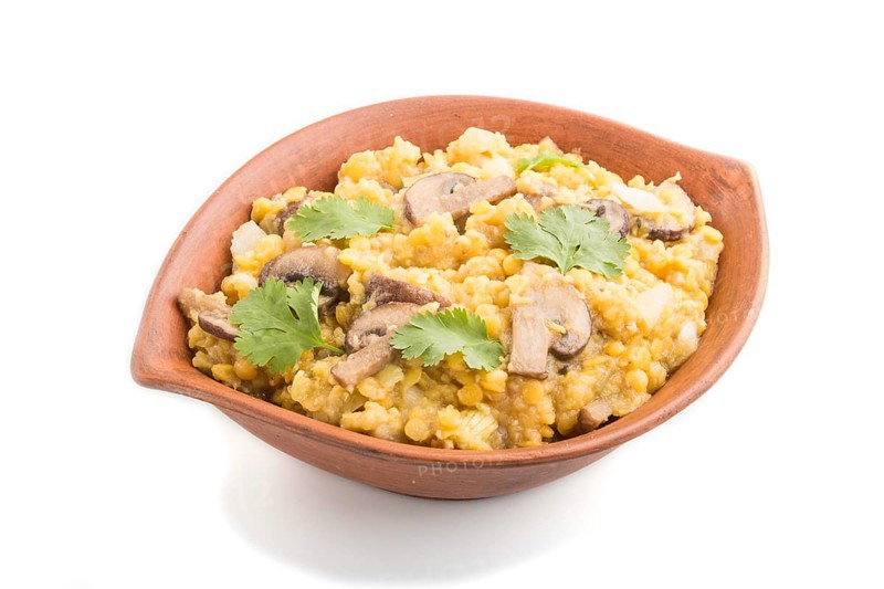 Lentils porridge with champignons and coriander in a clay bowl isolated on white background. Side view, close up