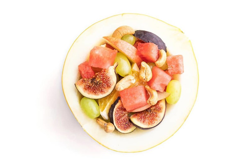 Vegetarian fruit salad of watermelon, grapes, figs, pear, orange, cashew isolated on white background. Top view, flat lay, close up