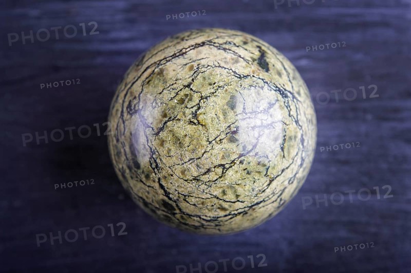 Green serpentine sphere on a black background, close up