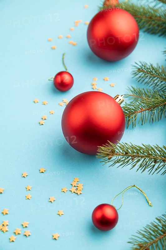 Christmas or New Year composition. Decorations, red balls, fir and spruce branches, on a blue paper background. Side view, copy space
