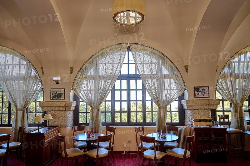 A bright café with large arched windows, wooden furniture and red carpets that exudes a warm, welcoming atmosphere, Elafos Hotel, Profitis Ilias, Rhodes, Dodecanese, Greek Islands, Greece, Europe