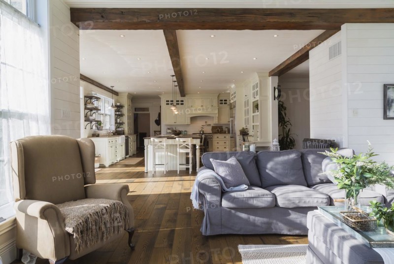Dark grey upholstered ektorp model sofa, bergere armchair in living room with rug and stained oak wood floorboards inside country style home, Quebec, Canada, North America