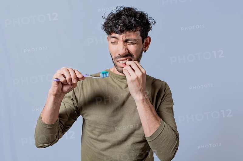 Young man holding toothbrush with gum pain. Man holding toothbrush with gum pain, People holding toothbrush with gum problem isolated