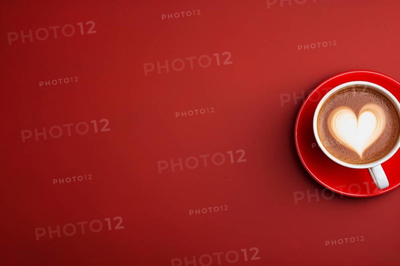 Top view of cup with coffee and heart shaped latte art on side of red background with copy space. KI generiert, generiert AI generated