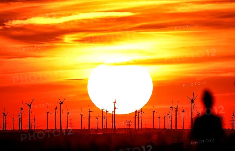 Joggers on Berlin's Drachenberg at sunset. A wind farm near Nauen in Brandenburg can be seen in the background, 23/08/2022