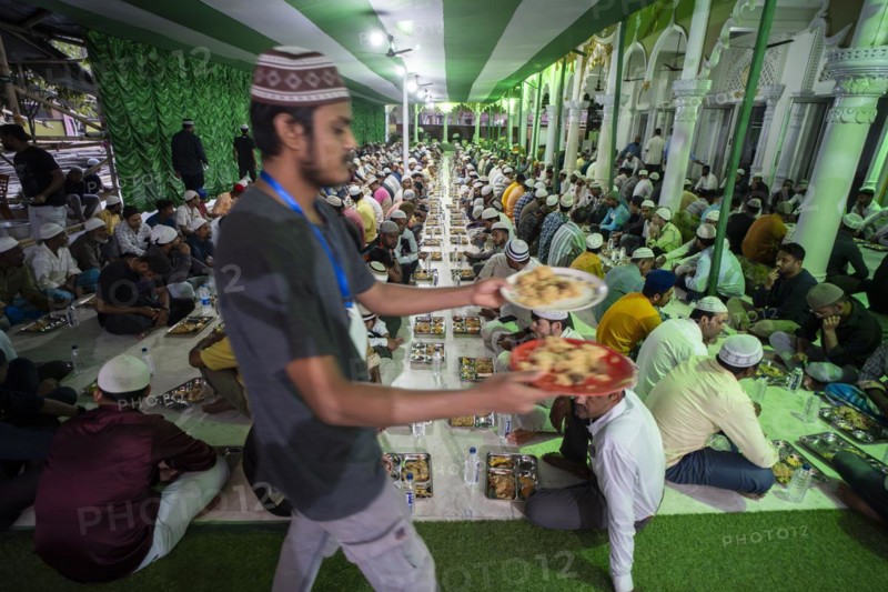 Volunteers distribute and arrange rows of 'iftar' meal for devotees to break their fast, during the holy month of Ramadan, at Burha Jame Masjid, on March 13, 2024 in Guwahati, Assam, India, Asia