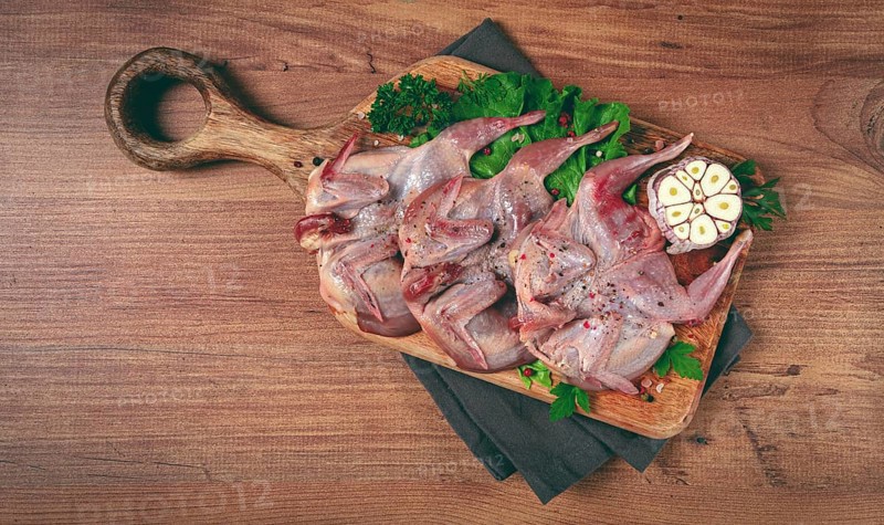Raw quail meat, on a cutting board, with spices and herbs, top view