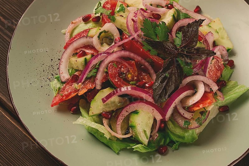 Georgian vegetable salad, tomatoes with cucumbers, red onion, walnut, pomegranate seeds, top view, no people