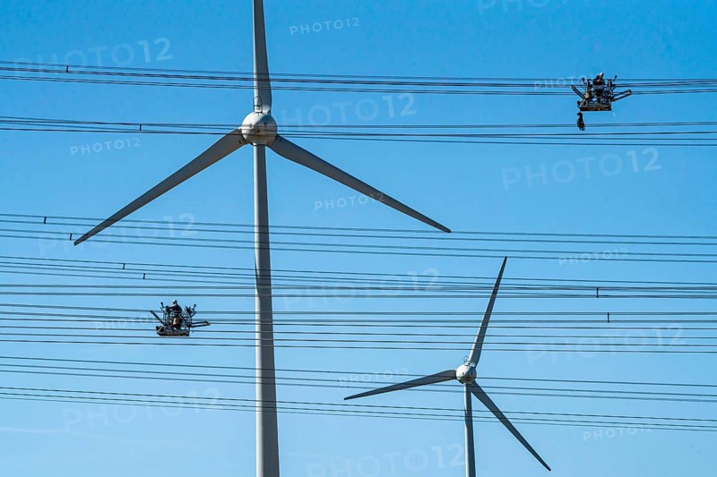 Construction of a new line route, 380 KV extra-high voltage line between Osterath and Gohr, near Neuss, fitters in cable trolleys, on the conductor cables, installing field spacers at great heights, wind power station, North Rhine-Westphalia, Germany, Europe