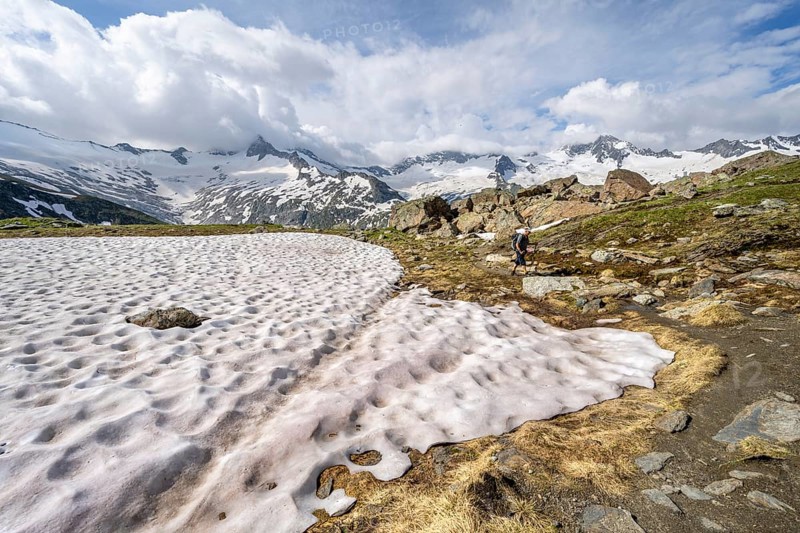 Mountaineers on hiking trail in picturesque mountain landscape, mountain peaks with snow and glacier Schwarzensteinkees, Hornkees and Waxeggkees, summit Schwarzenstein, Hornspitzen and Großer Möseler, Berliner Höhenweg, Zillertal Alps, Tyrol, Austria, Europe