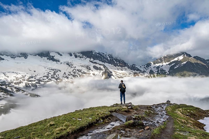 Mountaineer in front of mountain landscape with high fog in the valley, summit Hochfeiler and Hochsteller with clouds, glacier Schlegeiskees, Berliner Höhenweg, Zillertal Alps, Tyrol, Austria, Europe