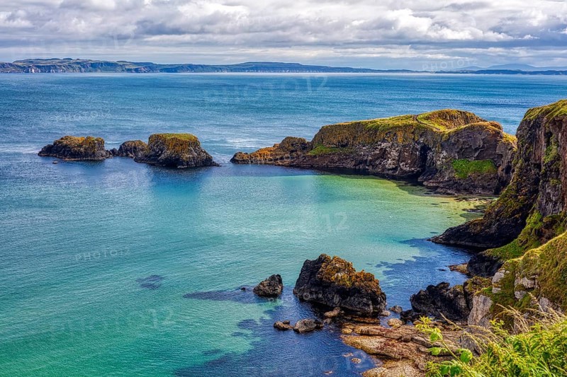 Steep cliffs overlook the clear blue-green sea under dramatic skies, County Antrim Coast
