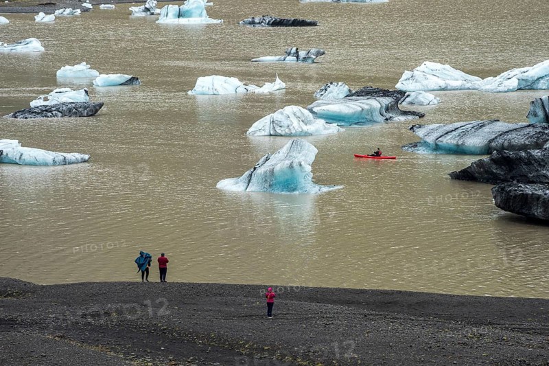 Single kayaker in red kayak, glacial lake at the glacier solheimajökull, icebergs on the lake, Iceland, Europe