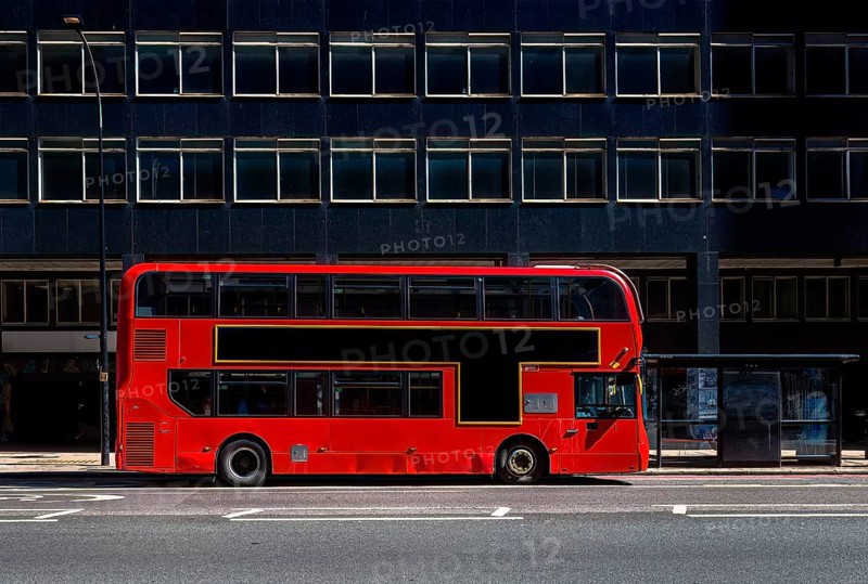Red double-decker bus on a city street with free advertising space or advertising banner in front of modern buildings, London, United Kingdom United Kingdom