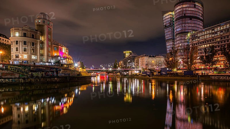 Lights reflected in the Danube Canal, on the left the Urania observatory, on the right illuminated office towers, night shot, Vienna, Austria, Europe