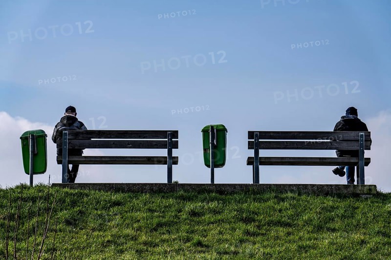 Benches on a dyke on the Weser in Bremerhaven, two people sitting symmetrically away from each other on the benches Bremen, Germany, Europe