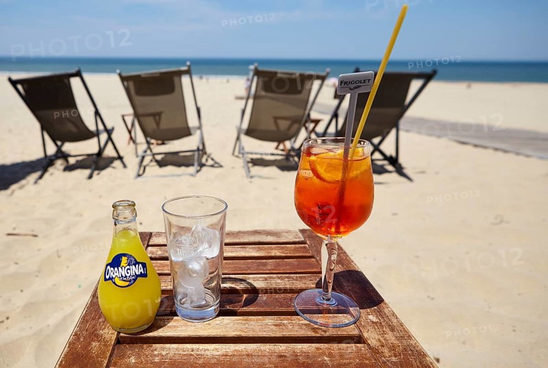 A bottle of Orangina, a glass with ice cube cubes and a glass of Aperol Spritz with a straw in a beach bar in Soulac-sur-Mer, Gironde, Nouvelle-Aquitaine, France, Europe