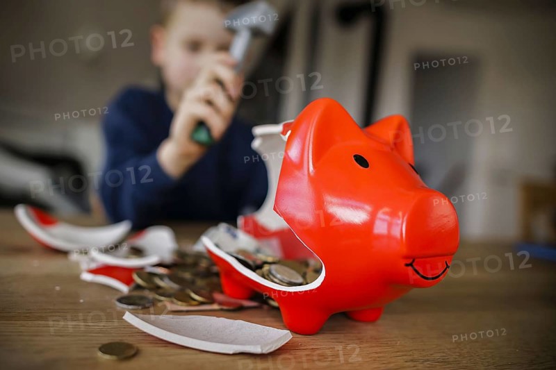 Symbolic photo on the subject of saving. A boy smashes his savings slip and counts the money it contains. Berlin, 10.02.2024