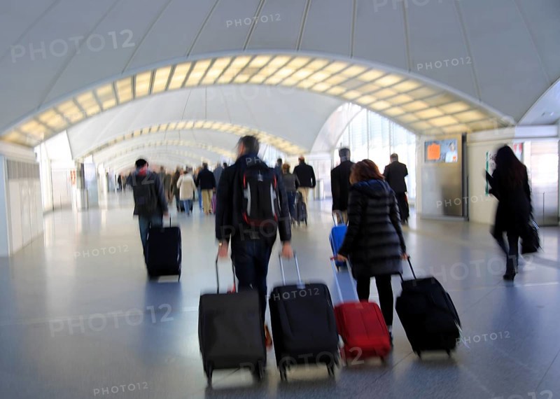 Blurred motion image of passengers pulling luggage bags along a bright corridor, Atocha railway station, Madrid, Spain, Europe