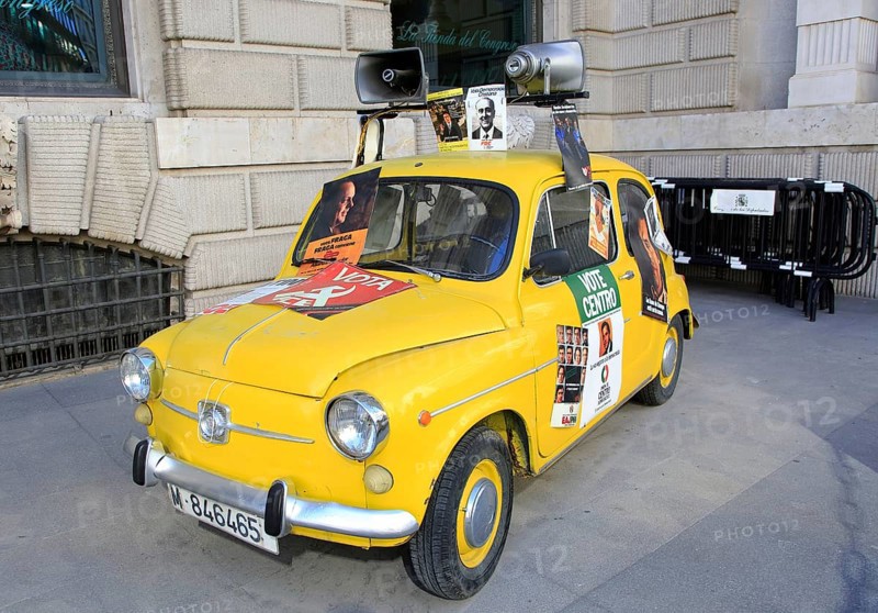Small yellow SEAT car with megaphones and political posters, Madrid city centre, Spain, Europe