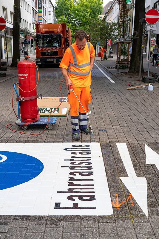 Application of road markings for a cycle lane, Rüttenscheider Straße in Essen, in the shopping and gastronomy district, cyclists have right of way over motorised vehicles, part of a cycle axis through Essen's city centre