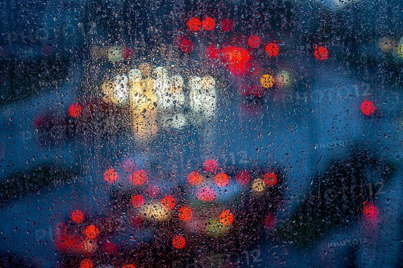 Rainy weather, road traffic, raindrops on a window pane, behind, blurred, lights of vehicles on a rain-soaked road, traffic light, tail lights, headlights, symbolic image